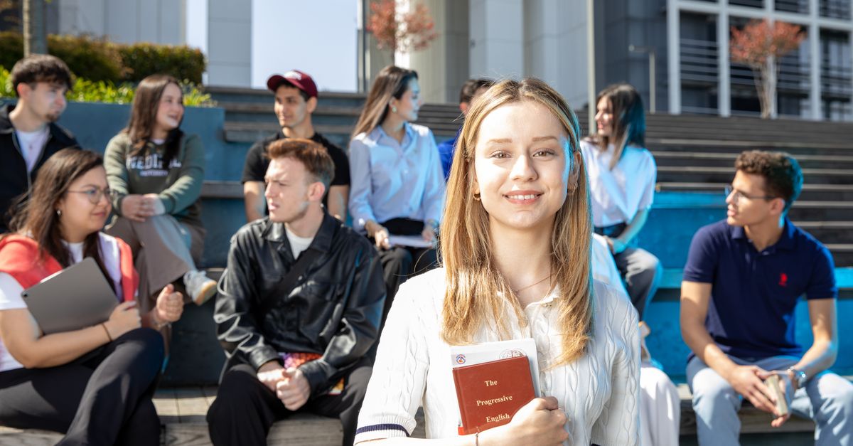 Groupe de jeunes adultes socialisant sur les marches de l'université, discutant et étudiant ensemble.