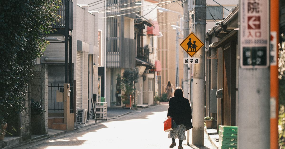 Une rue japonaise sereine avec des passants marchant sous le doux soleil d'hiver, capturant la vie quotidienne.