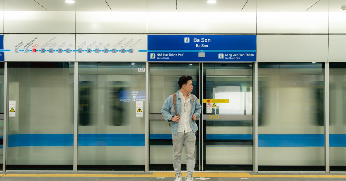 Un homme se tient à la station de métro Ba Son, attendant le train dans une station de métro moderne.