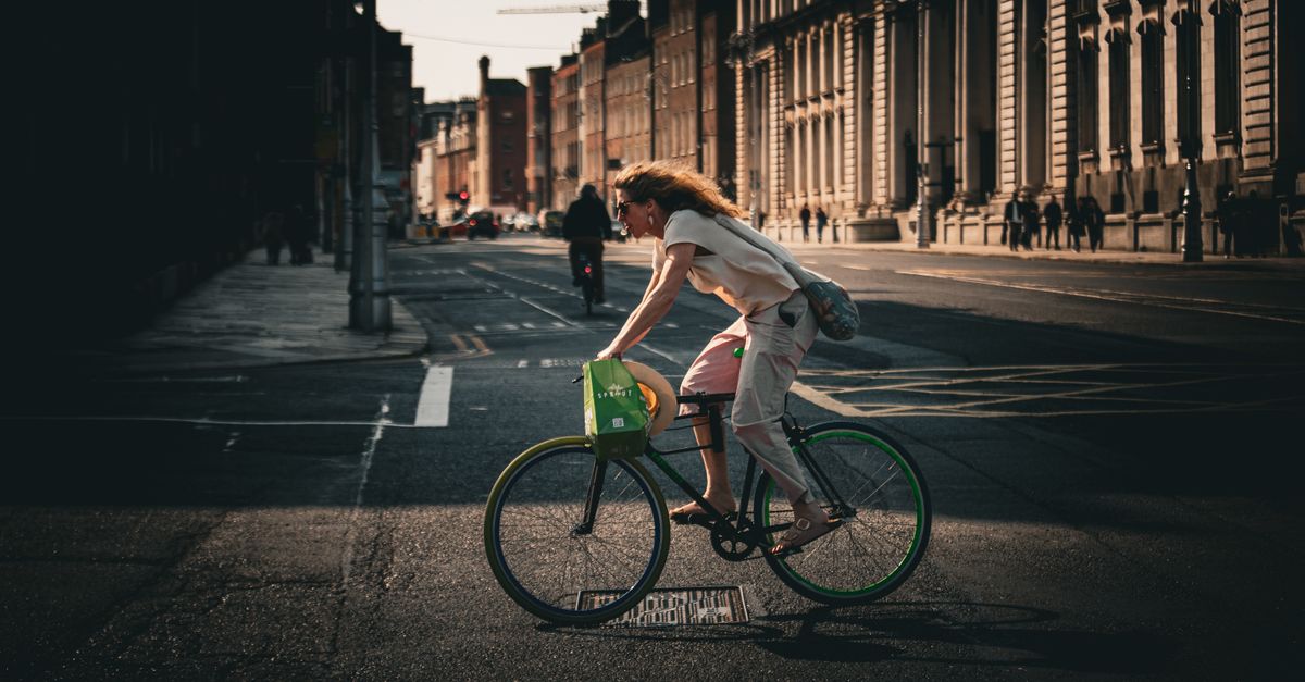 Une femme faisant du vélo dans les rues de la ville de Dublin sous la douce lumière du matin, capturant le style de vie urbain et le mouvement.