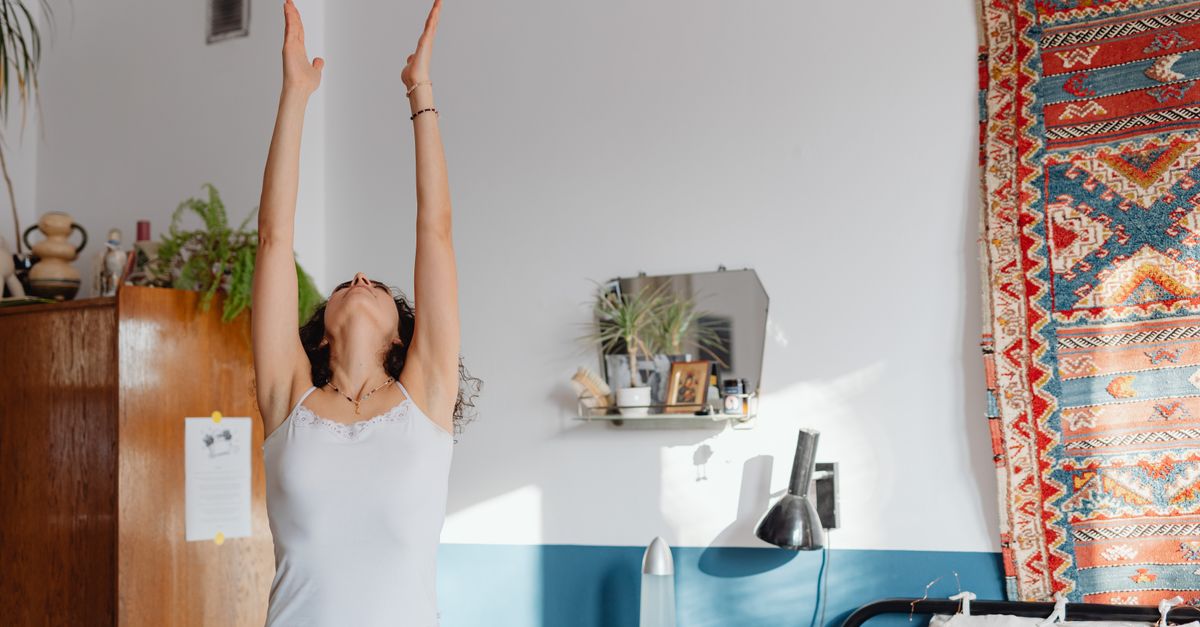 Une femme pratiquant le yoga à l'intérieur, s'étirant les bras levés, embrassant le bien-être.