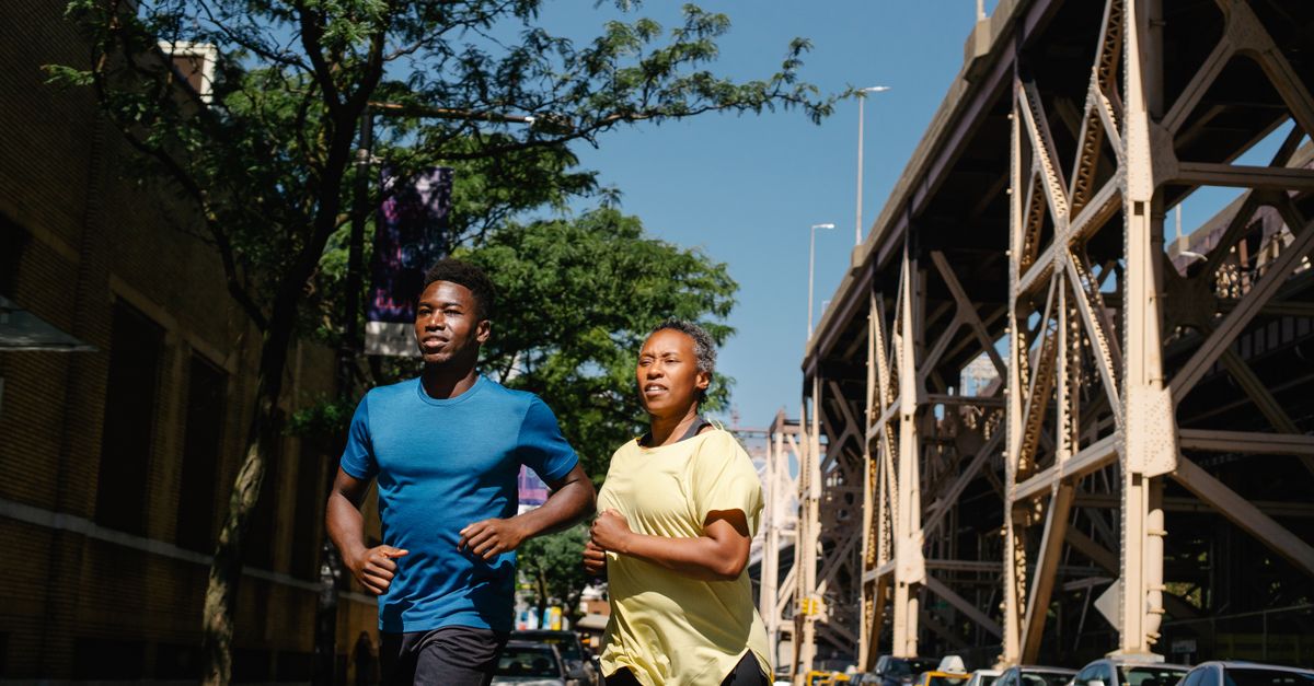 Image dynamique d'un couple courant dans une rue ensoleillée, promouvant la forme physique et le bien-être.