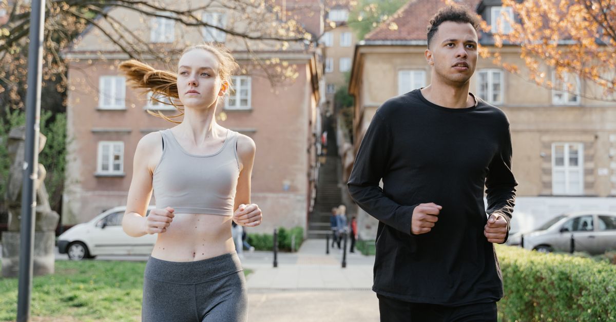 Un jeune homme et une jeune femme courant dans une rue de la ville pendant la journée, portant des vêtements de sport.