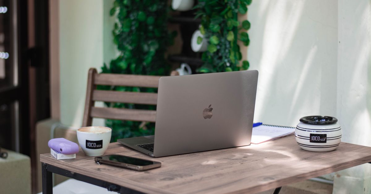 Un espace de travail confortable dans un café avec un ordinateur portable, une tasse de café et un smartphone sur une table en bois, idéal pour le télétravail.